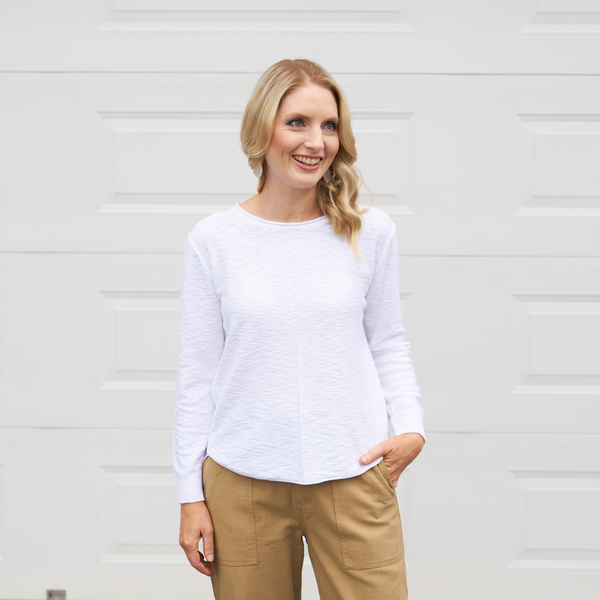 Sasha Knit Top in white. Features a round neckline, long sleeves and a curved hemline