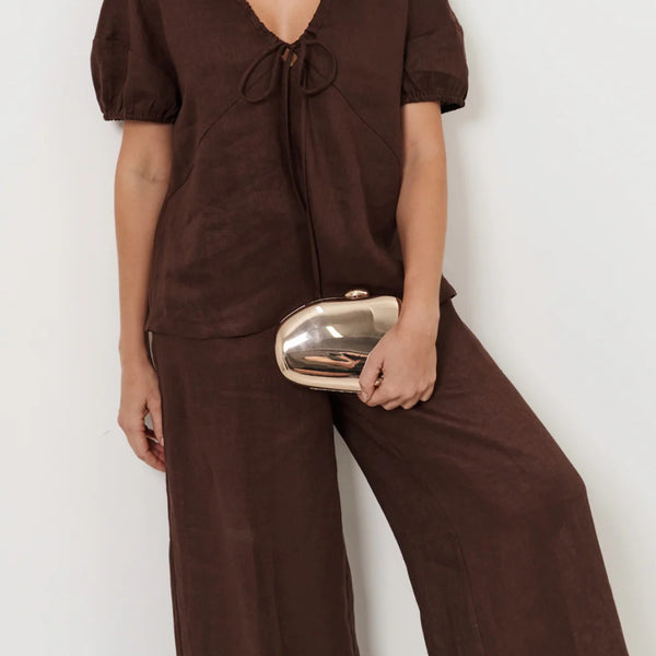 Model carrying our Abstract Curved Metal Clutch in a shiny gold.