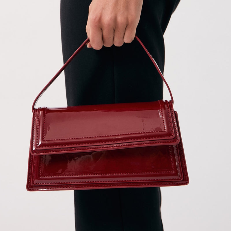 The bag is a compact size, it has a shoulder strap and a fold-over closure.