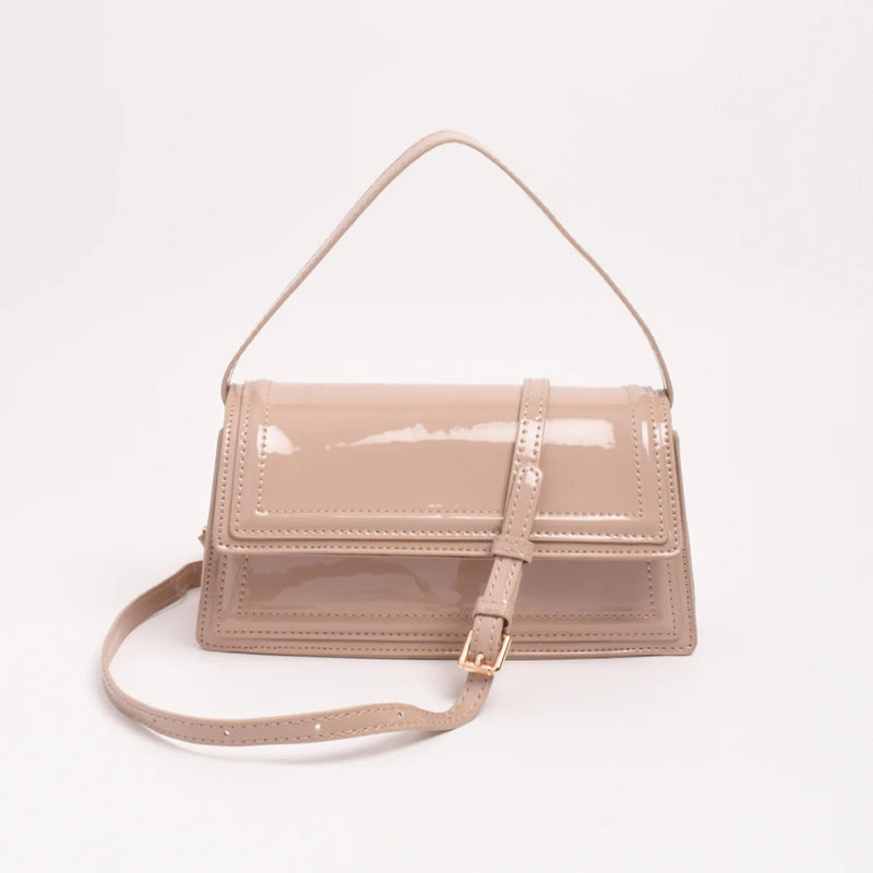The handbag has a fold over flap and a fixed shoulder strap.