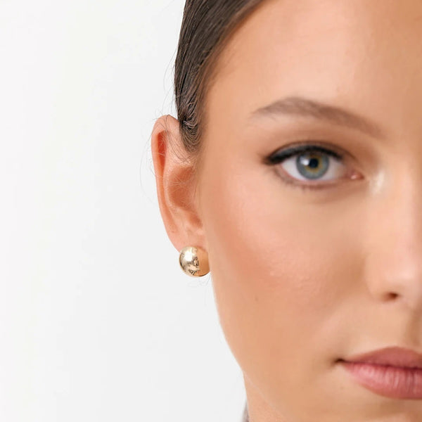 Model wearing these dome shaped earrings in gold.