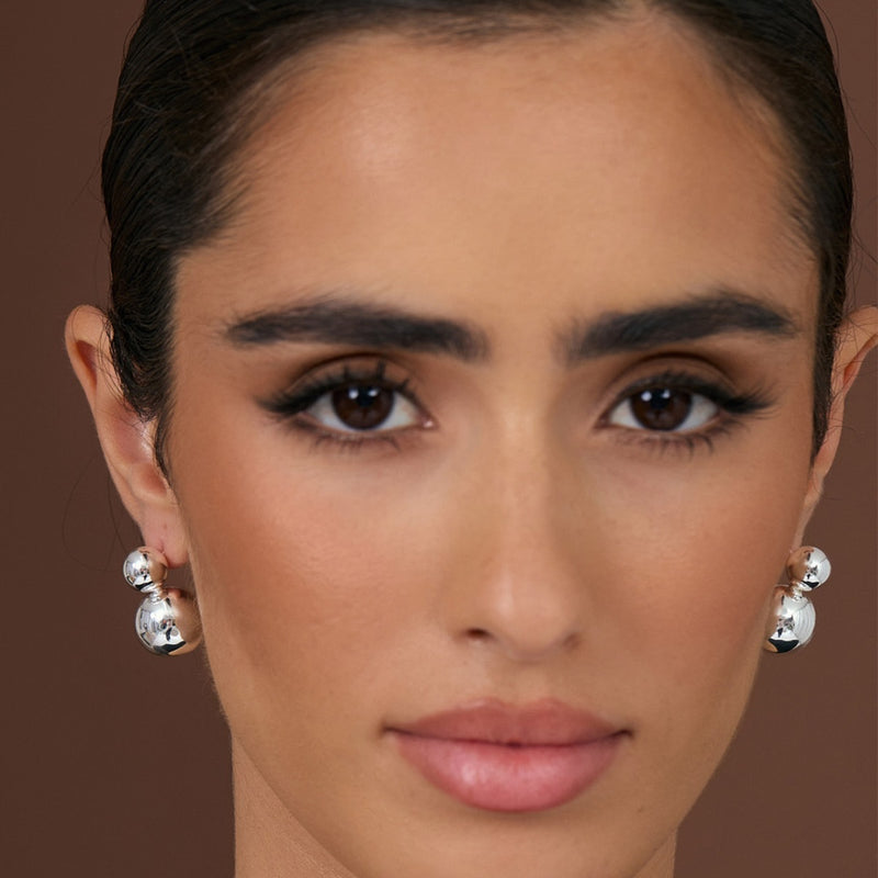 Inspo image with model wearing the silver version. These earrings have a double ball drop.