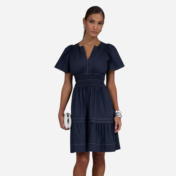 This dress features a round neckline with V cut-out, short sleeves, shirred waist and a tiered short skirt.