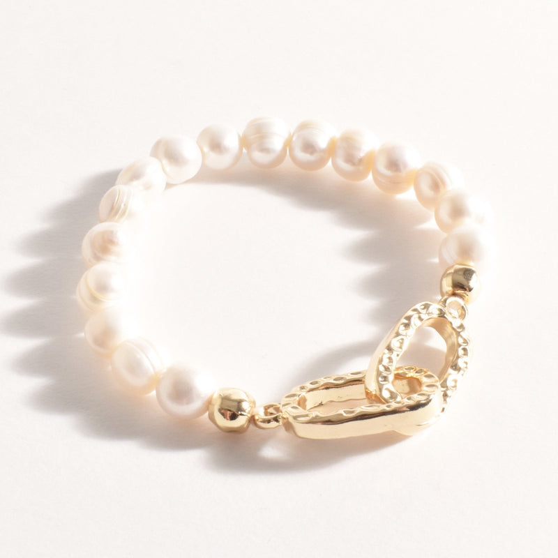 This stretch bracelet features freshwater pearls and two entwined beaten gold links