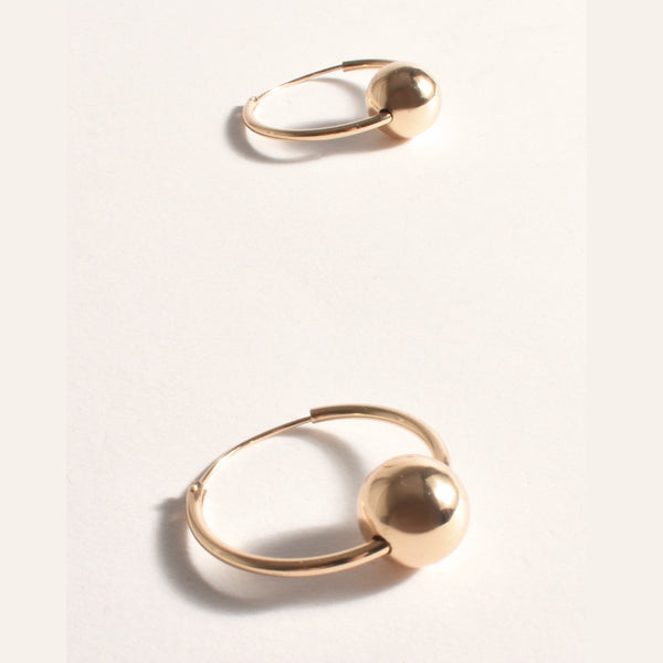These gold hoop earrings have a metal ball detail and a clip in back closure
