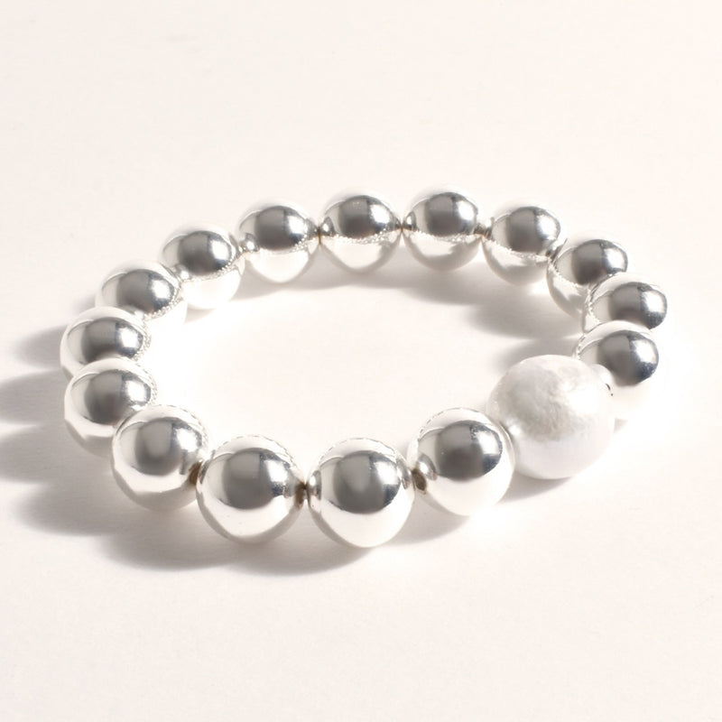 This bracelet features chunky silver metal balls and a freshwater pearl in the centre