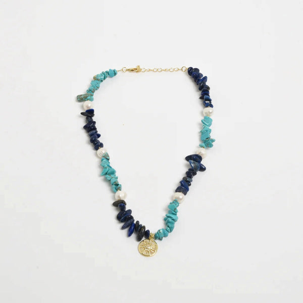 This necklace has a mix of blue stone chips, freshwater pearls and a gold sun charm.