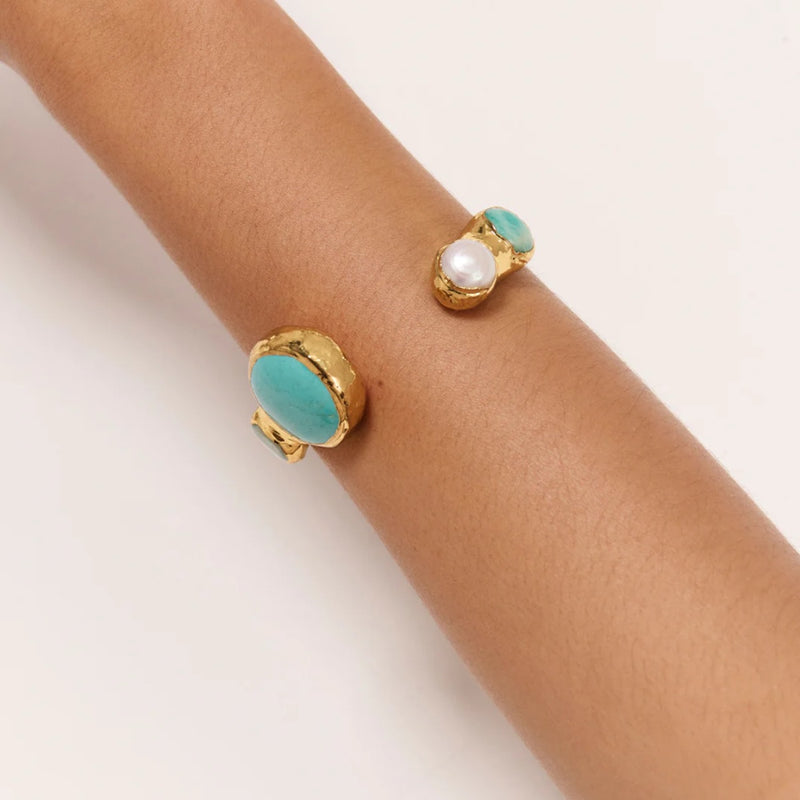 This gorgeous open bracelet has turquoise stones and a faux pearl.