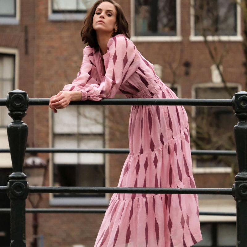 The dress features long sleeves and a tiered maxi skirt.