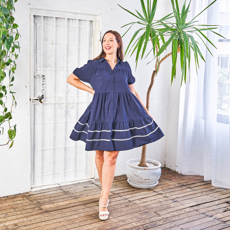 This navy dress has a collar, button front and a tiered skirt sitting above the knee
