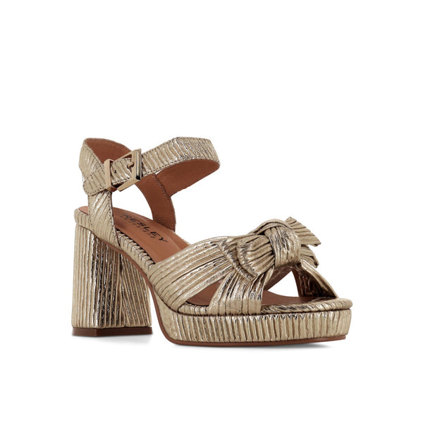 These metallic gold platform heels feature a bow detail on the front