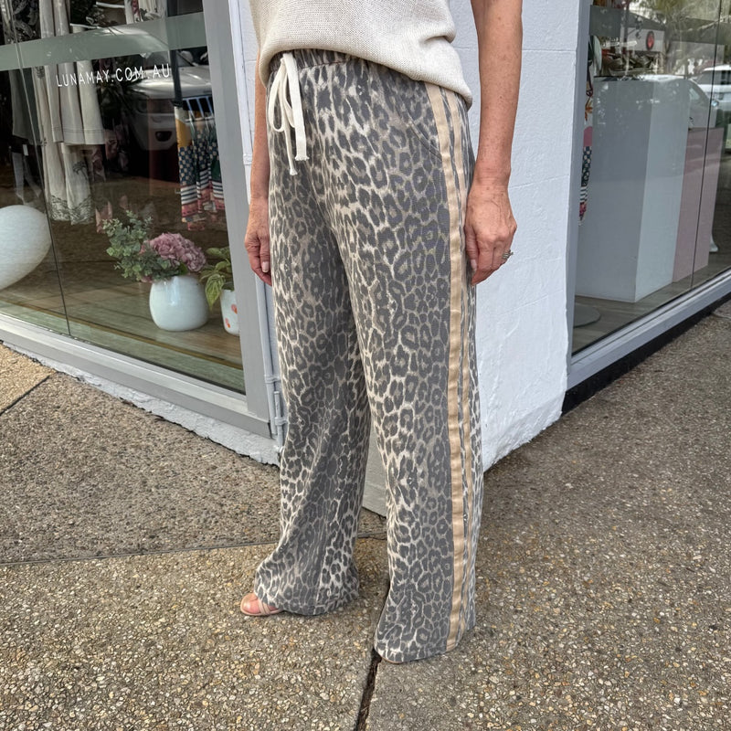 Side view of the pants and they have a beige silky stripe down the outer side.