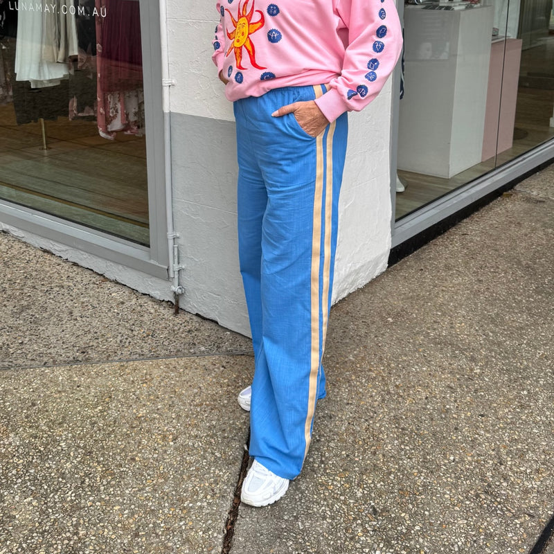 Side view of the pants with two cream side stripes and front pockets.