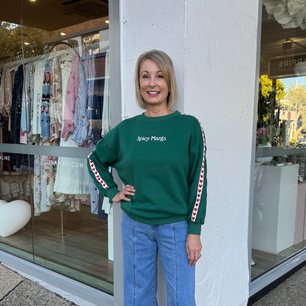 Spicy Margs green sweater with a cream and red heart stripe down the sleeve.
