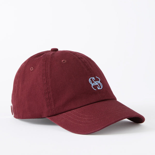 This burgundy cap has a blue embroidered monogram logo on the front.
