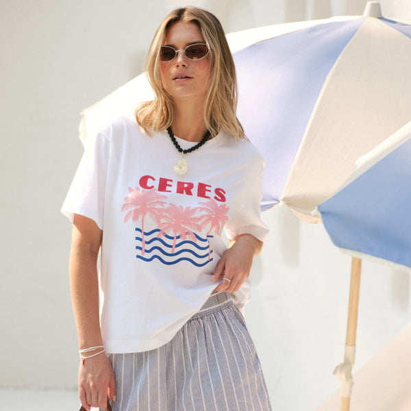 Stevie Slouchy Tee in white with Ceres on the front along with a beach inspired print - pink palm trees and blue waves.