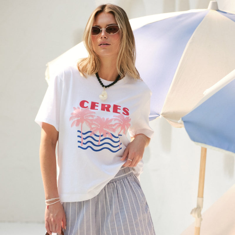 Stevie Slouchy Tee in white with Ceres on the front along with a beach inspired print - pink palm trees and blue waves.