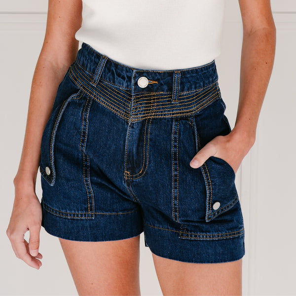 These denim shorts have a tailored shape, fold over pockets with fastening and contrast tan stitching. They also have a zip and button closure.