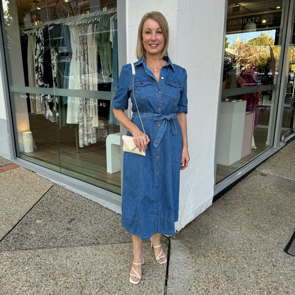 This stylish denim dress features a collar, short sleeves, button front, chest pockets, detachable belt and a midi length skirt