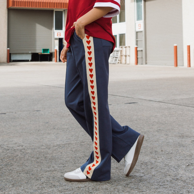 Side view of the pants and the cream stripe with the red hearts running down the side of the leg.