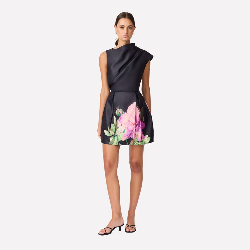 Our Azelie Dress is absolutely stunning. This black mini dress has an asymmetrical neckline and a tulip skirt with a floral motif.