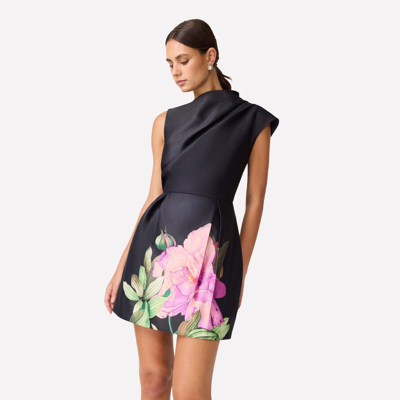 This sleeveless dress has a fitted waist and the skirt has a pink and green floral motif.