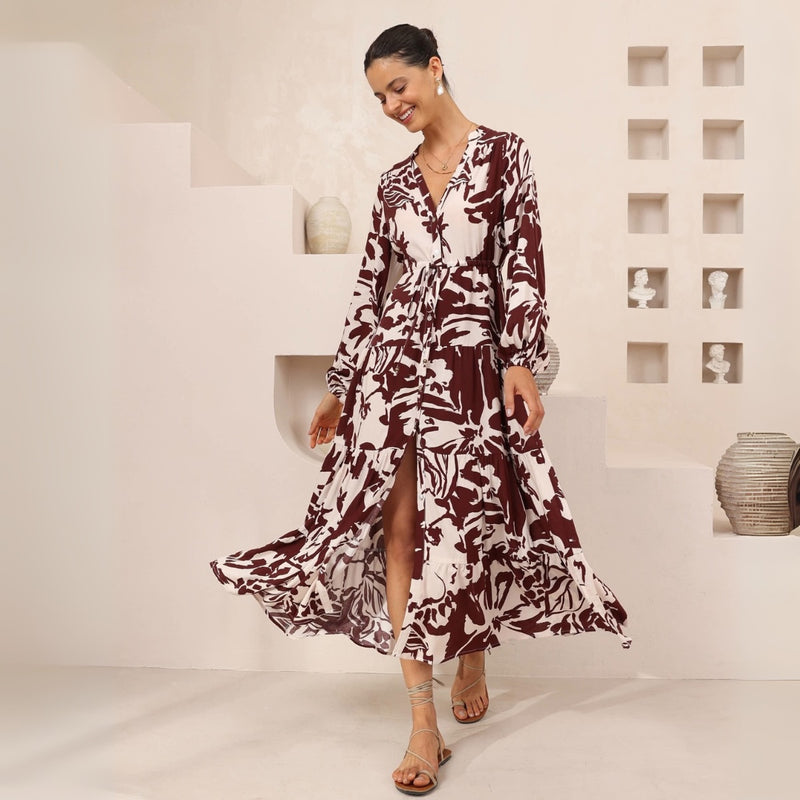 The dress features a V neckline, button front, drawstring ties under the bust, long sleeves with elasticated cuffs and a tiered midi skirt.