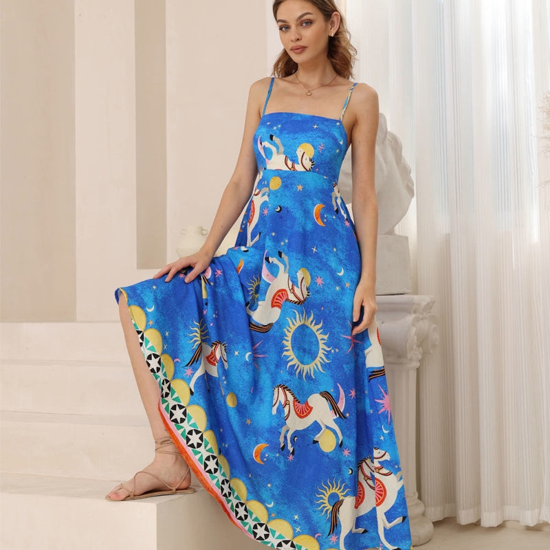 Our Dominica Maxi Dress has a bright blue base with a colourful horse, sun and moon print in white, yellow, pink, red and black.