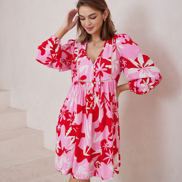 This dress has a lovely pink, red and white floral print. Features a V neckline, embroidery detailing along the bodice, long sleeves and a short skirt
