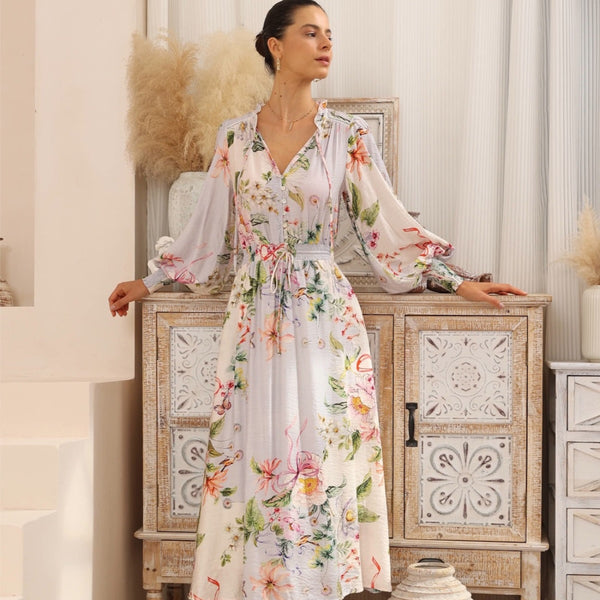 The dress has a V neckline, long sleeves and a drawstring waist. The midi length skirt has a loose flowing shape.
