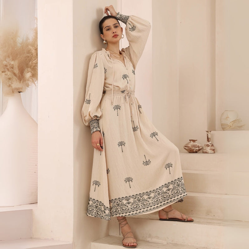 The dress has a shirred waist with drawstring ties, long sleeves and a full maxi length skirt.