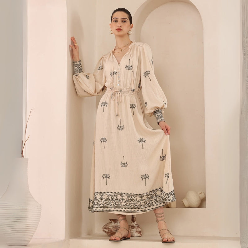 Our Oliana Dress has a cream coloured base with khaki coloured embroidered palm tree accents and a contrast khaki embroidered accent on sleeve cuff and hem.
