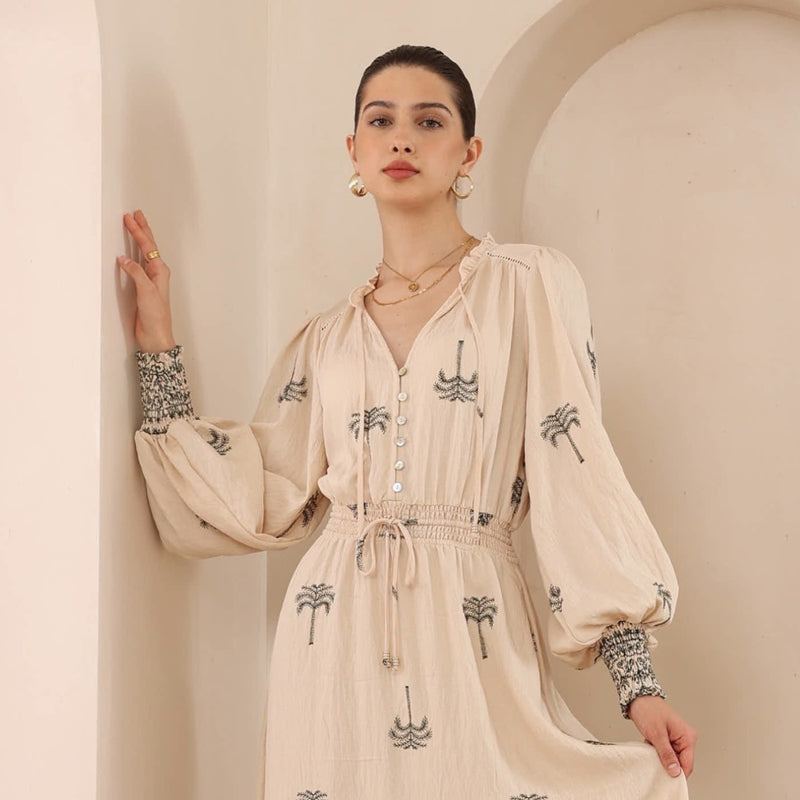 Close up of the bodice - features a ruffle neckline, V cut-out with neck ties, long sleeves with shirred cuffs, a button bodice and a shirred waist with drawstring ties.