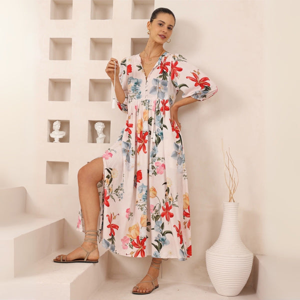 The dress has a round neckline with neck ties, half length sleeves, gathered detailing under the bust and a maxi length skirt with side splits.