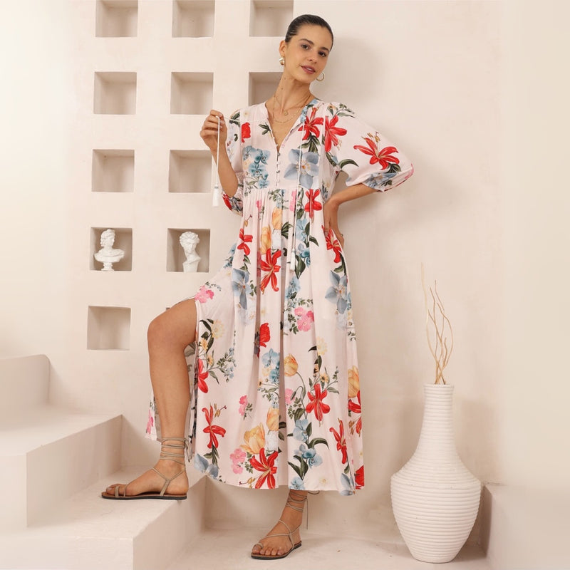 The dress has a round neckline with neck ties, half length sleeves, gathered detailing under the bust and a maxi length skirt with side splits.