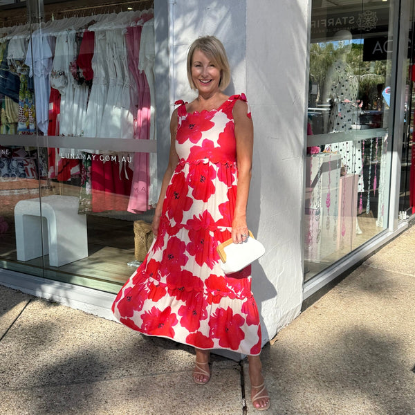 Tanya wearing our Hibiscus Dress. It has a bold red and cream floral print, tiered skirt and finishes midi length.