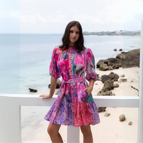 Our Cynthia Floral Dress by Kachel has a vibrant floral print with pink, purple, teal and grey tones.