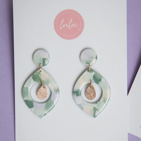 These resin dangle earrings have a single stud, cut-out petal shape dangle and a rose gold leather accent.