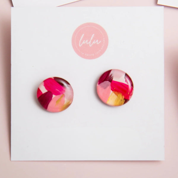 Pair of round earrings with pink and gold design. These Mulled Horizon Stud Earrings are lightweight and handmade.