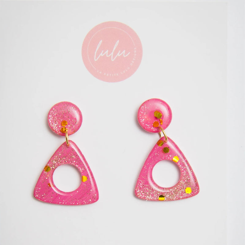 Our Triangle Resin Dangle Earrings (Rose Reverie artwork) has a triangle shaped dangle suspended from a single stud. These sparkly pink and gold earrings are lightweight.