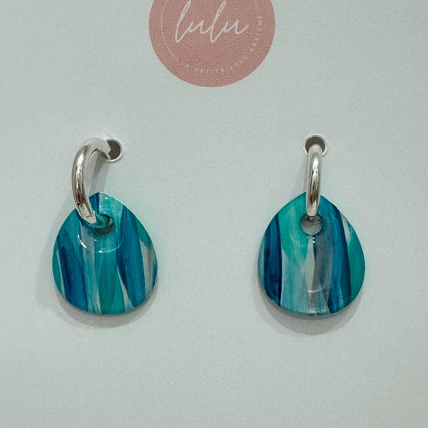 Isabella Huggie Earrings with a silver huggie and a teardrop resin shaped drop in teal tones