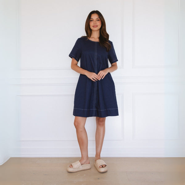 Our Aniston Shift Dress in navy, has contrast white top stitching along the neckline, sleeve edge, hem and vertically down the centre and back.