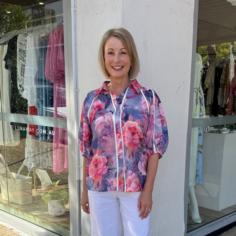 the shirt has a collar, button front, half length sleeves and a loose fit body.
