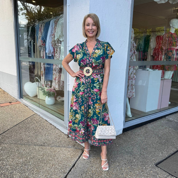 Our Kacey Floral Dress has a deep green base with pink, burgundy, white and yellow floral print.