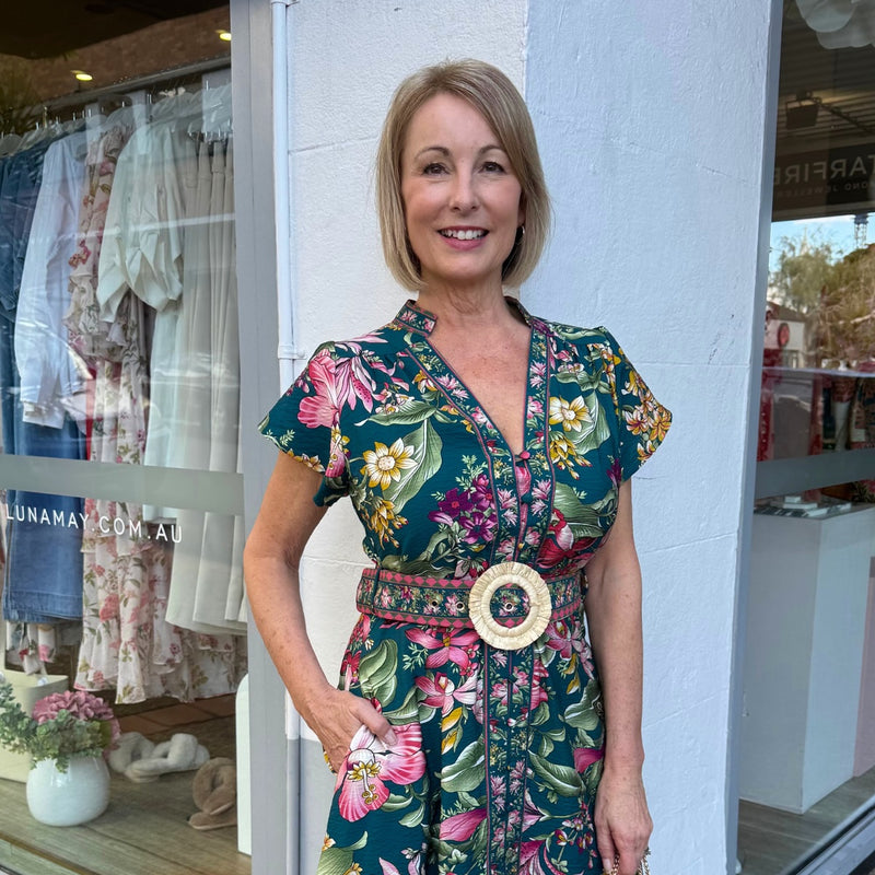 Close up of the bodice area - it has a mock collar, V neckline, cap sleeves, button front and a statement self print belt finished with a raffia buckle.