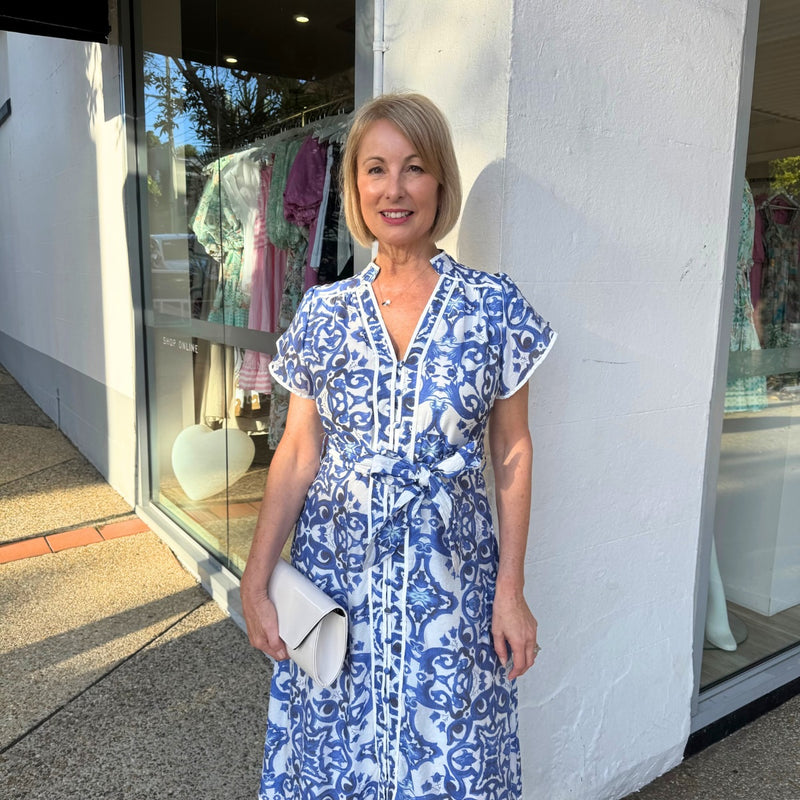 Close up of the bodice area  - it has a mock collar, V neckline, button front, flutter sleeves and contrast white stripes on the neckline, button front, sleeve edge.