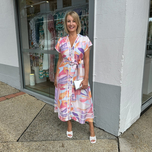 The dress has an Aline midi length skirt and contrast white ribbon detailing along the mock collar, button front and along the hem.