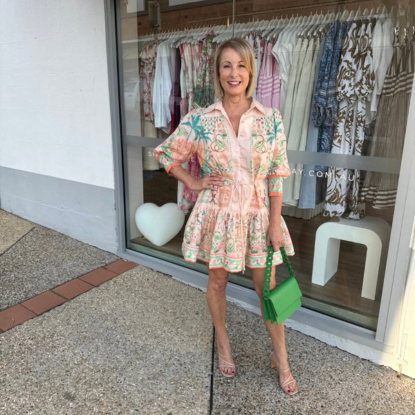 Aurora Cove Mini Dress has a tropical inspired print with a peach base and blue, green and orange accents.