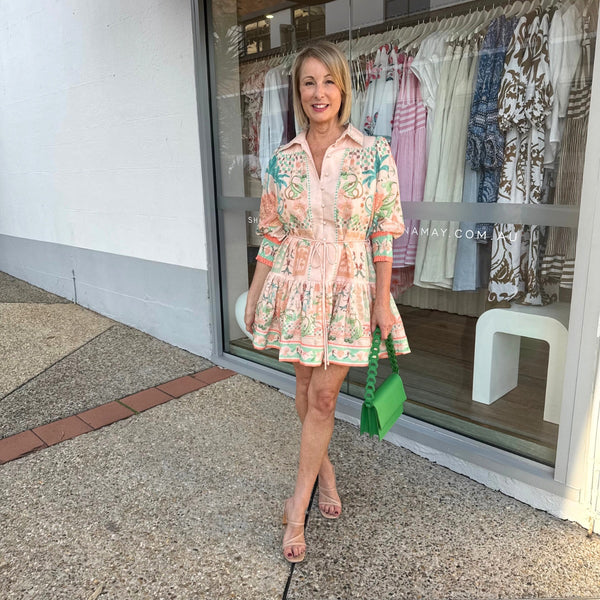 The dress has a collar, button front, half length sleeves and a frill hem.