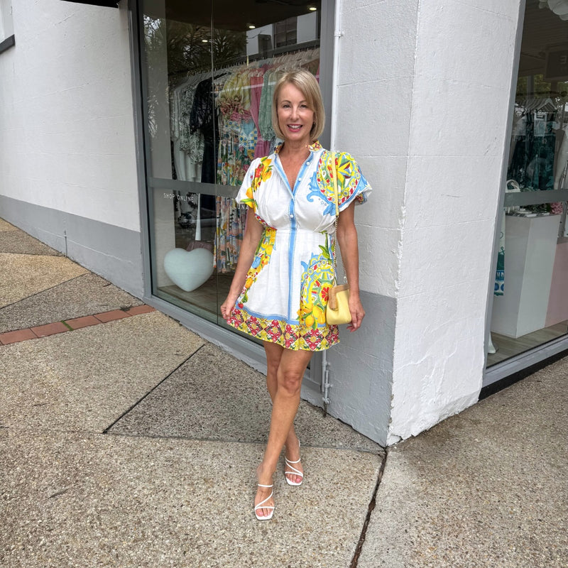 Tanya wearing our White Coast Dress. It can be accessorised with heels and a yellow clutch.